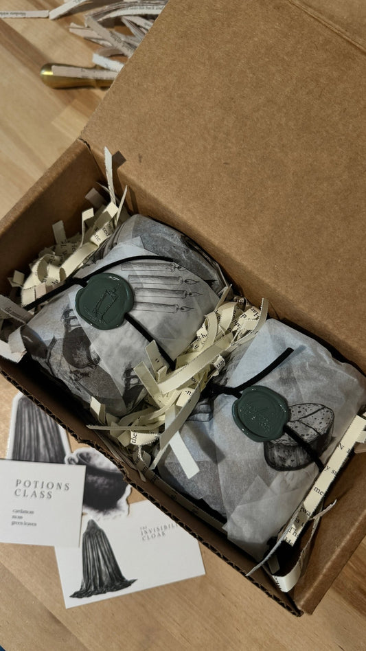 Two candles gift wrapped in book inspired packaging, sealed with wax