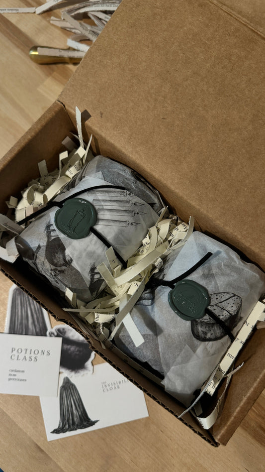 Two candles gift wrapped in book inspired packaging, sealed with wax