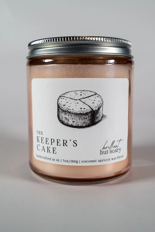 The Keeper's Cake bookish candle with silver lid and pink glass jar - Brilliant but Scary luxury candles