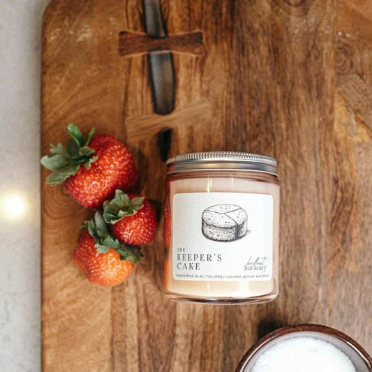 The Keeper's Cake magical fantasy book candle next to fresh strawberries.
