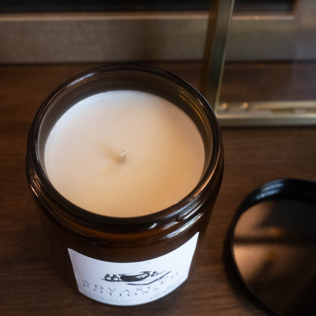 Candle in a glass jar with a label on a wooden surface