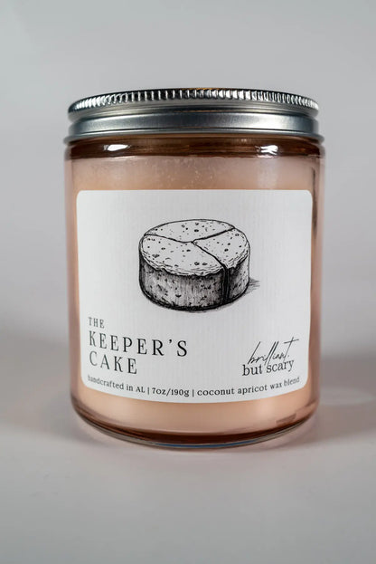 The Keeper's Cake bookish candle with silver lid and pink glass jar - Brilliant but Scary luxury candles
