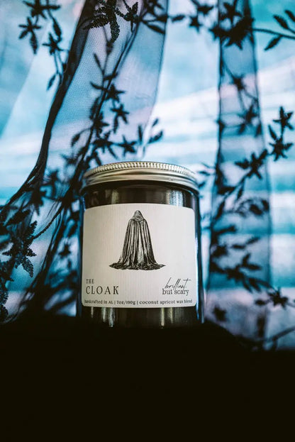 The Cloak fantasy candle in navy jar underneath an embroidered cloak - Brilliant but Scary
